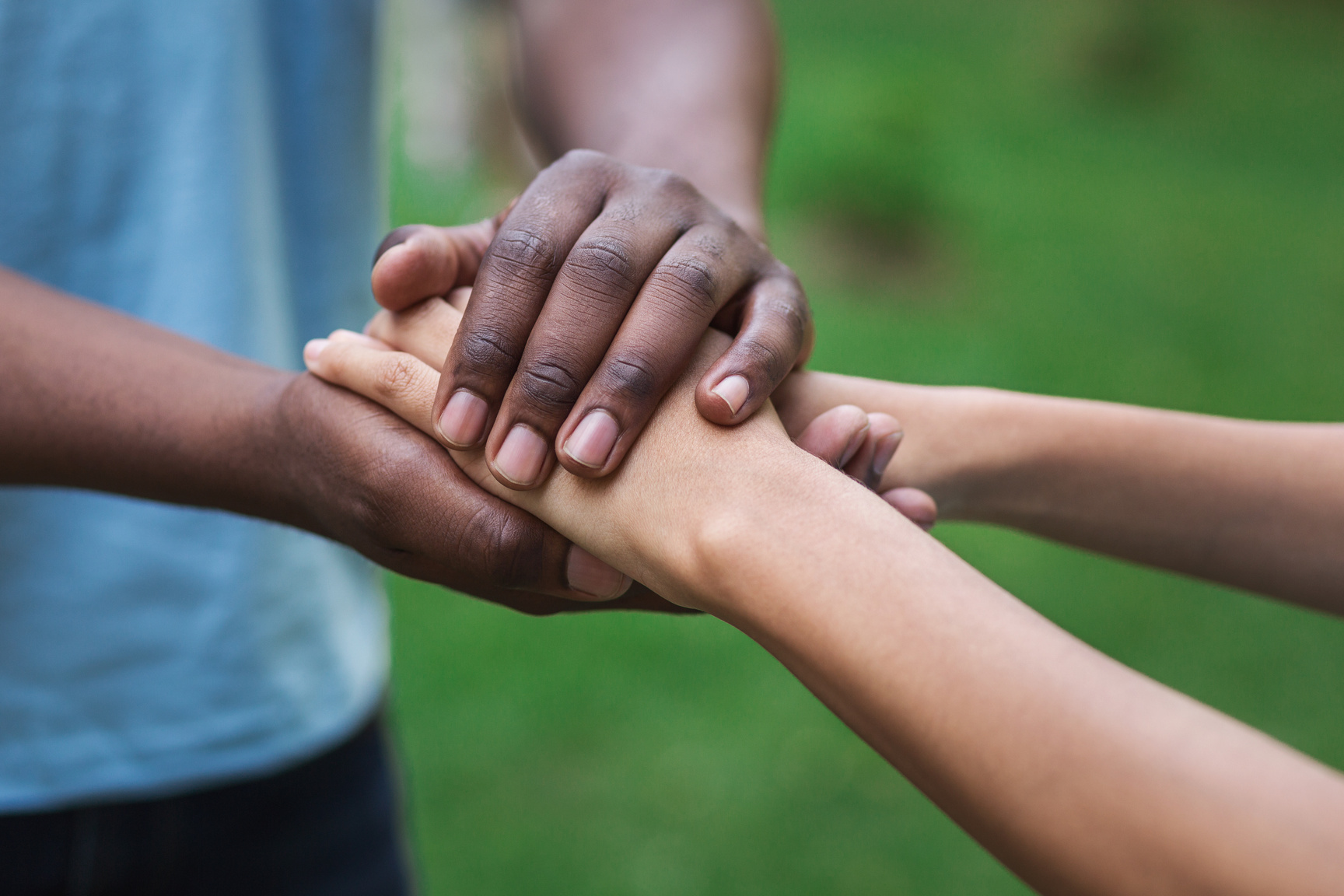 Black caregiver supporting woman hand in park